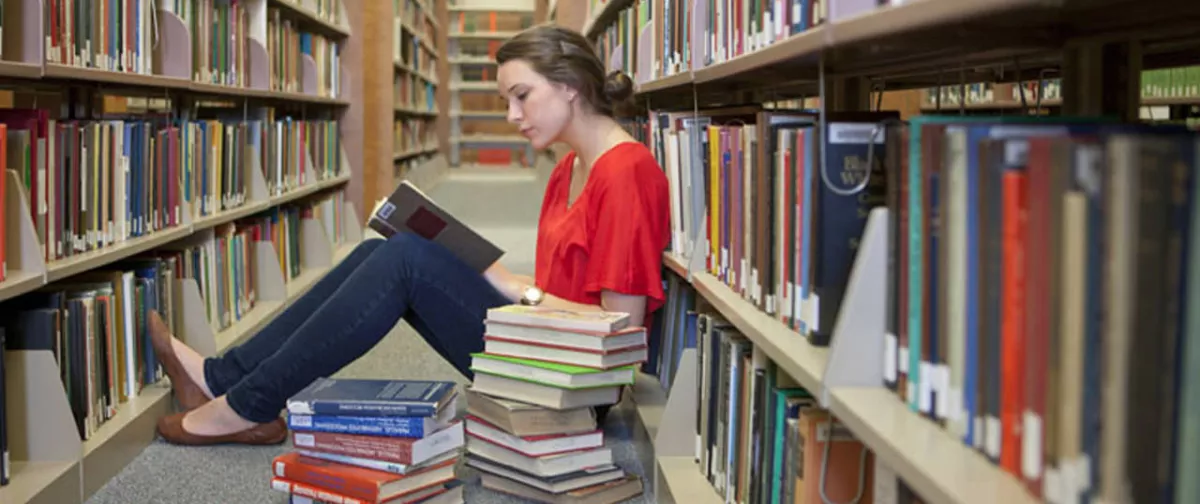 A girl reading a book in a library.