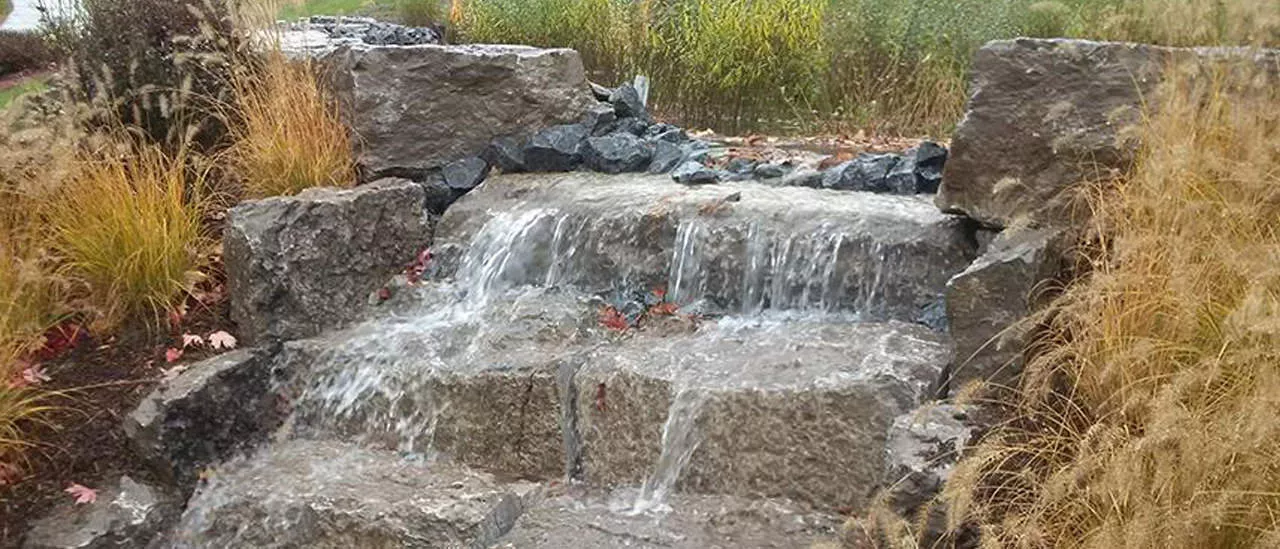 Water overflowing as designed down a set of stone blocks into the fifth basin.