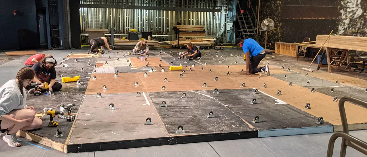 Students fix casters on the bottom of a rotating set