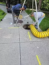 Two workers preparing an opening into a confined space work area.