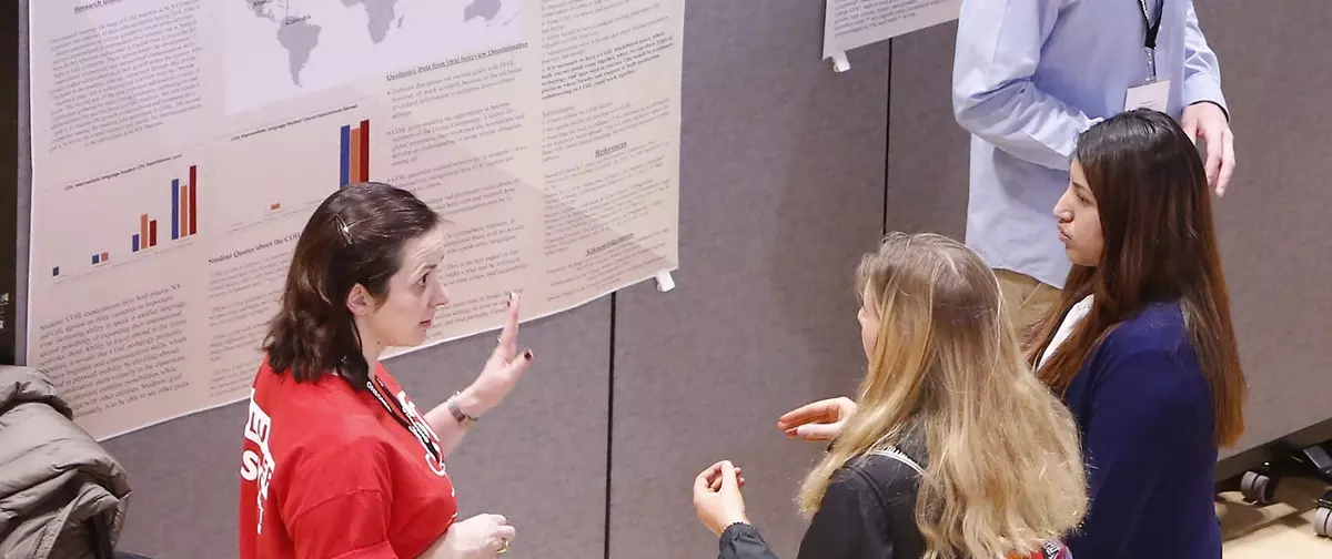 3 women standing around a presentation.