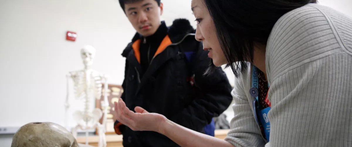 Professor Sallie Han presenting a human skeleton to a guest on campus.