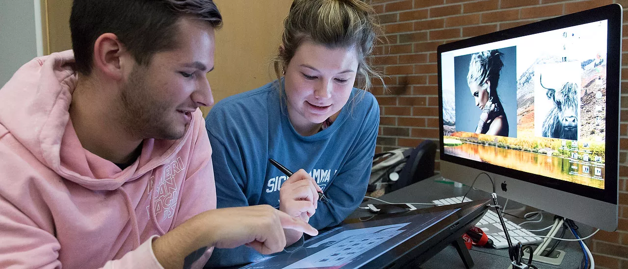 Computer art students working together on a tablet.