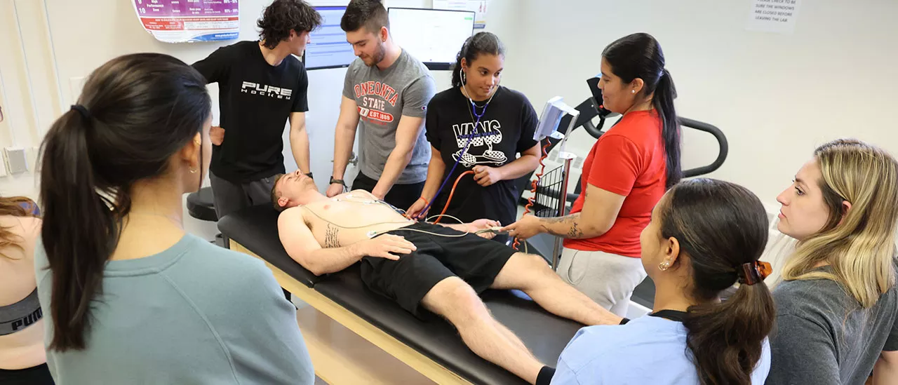 Students measuring the biometrics of another student laying on a table.