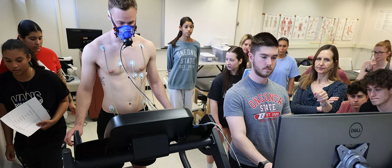 Students measuring the biometrics of another student on a treadmill.