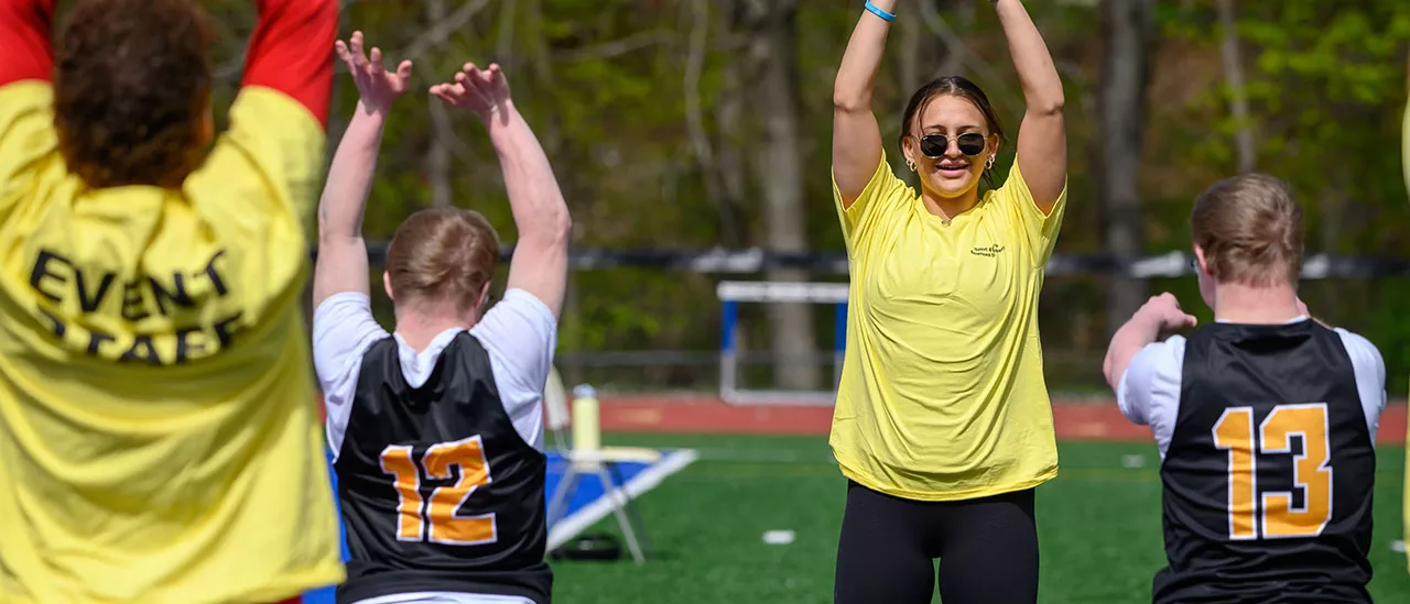 Event staff stretching with athletes before the special Olympics.