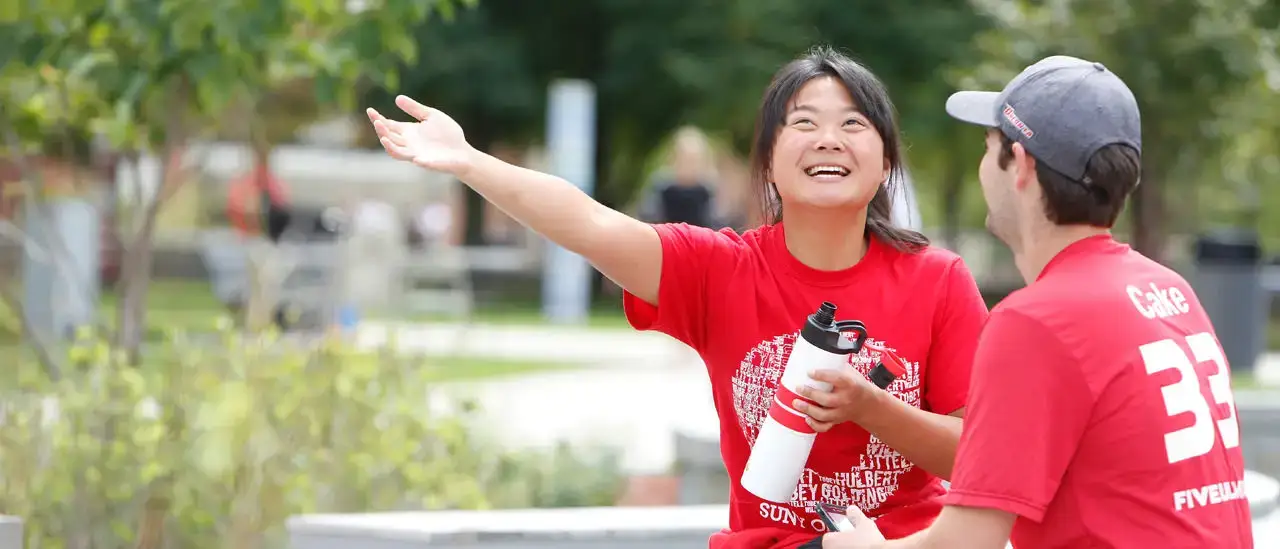 Students having a conversation wearing red day shirts in the quad