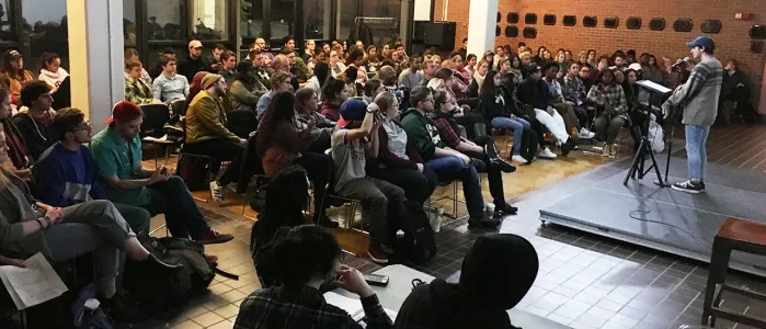 Student reading poetry in front of a large crowd.