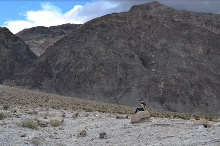 Student sitting on a boulder in the Bad Lands