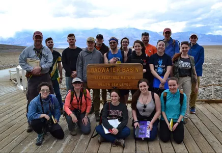 Students and faculty posing in front of a sign in the Bad Lands